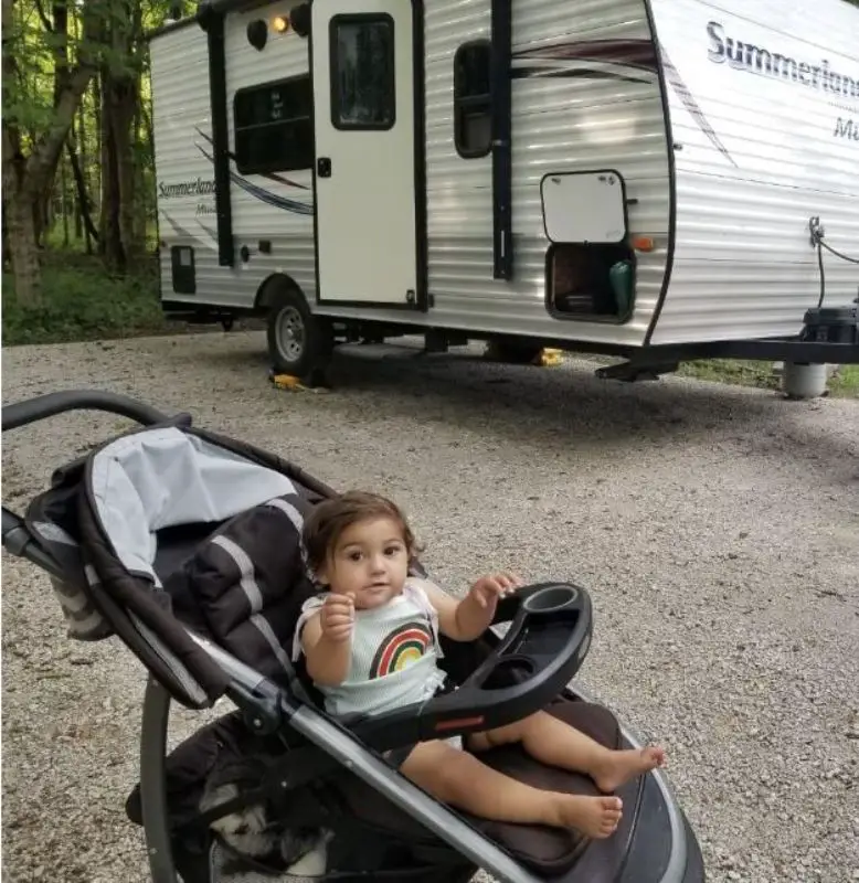 baby in stroller in front of travel trailer