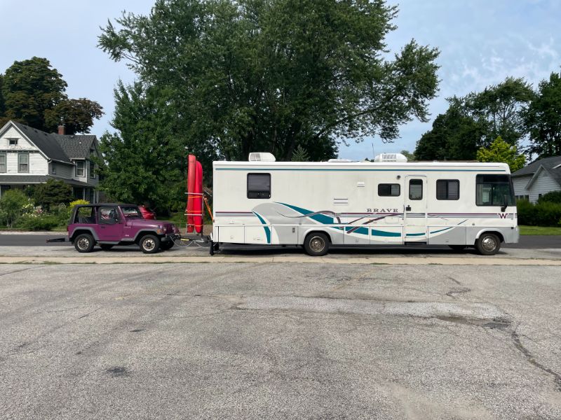 White RV Parked In Front Of Purple Jeep